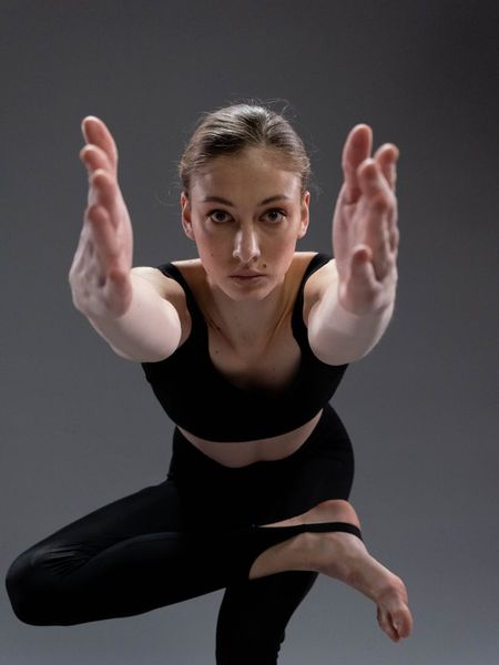 Woman in a graceful yoga pose against a dark, calm background.